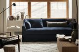 Wohnzimmer mit blauem Sofa vor Fensterfront