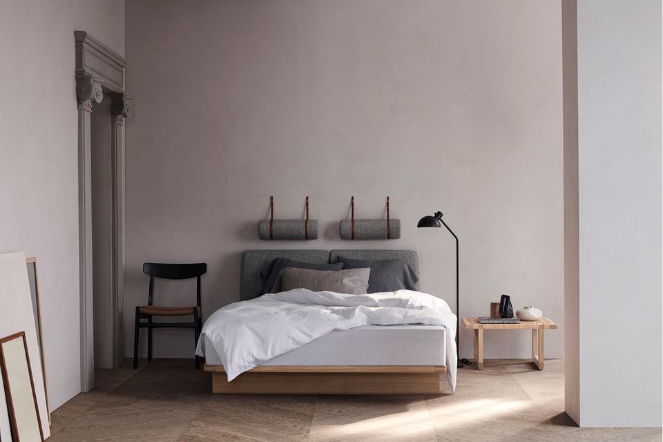 Modernes Bett mit Kopfpolstern und weißer Bettwäsche in einem dezent dekorierten Raum
