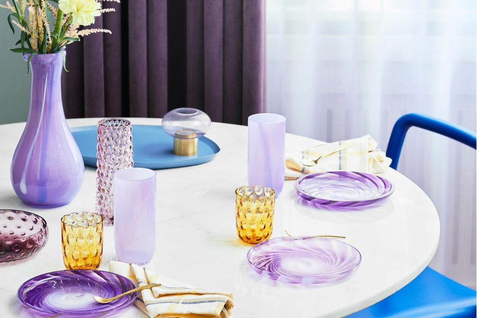 Blau und Violett ergeben ein harmonisches Bild. Vasen und Gläser in Violett auf dem Tisch