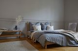 Schlafzimmer mit grauen Kassettenwänden und Textilien in Grau