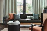 Raum mit grünen Vorhängen, Sofa, Sessel und Couchtisch