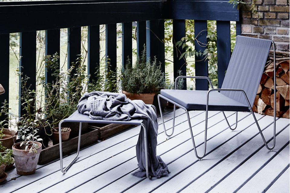 Schlichte graue Gartenmöbel auf einer hellen Veranda