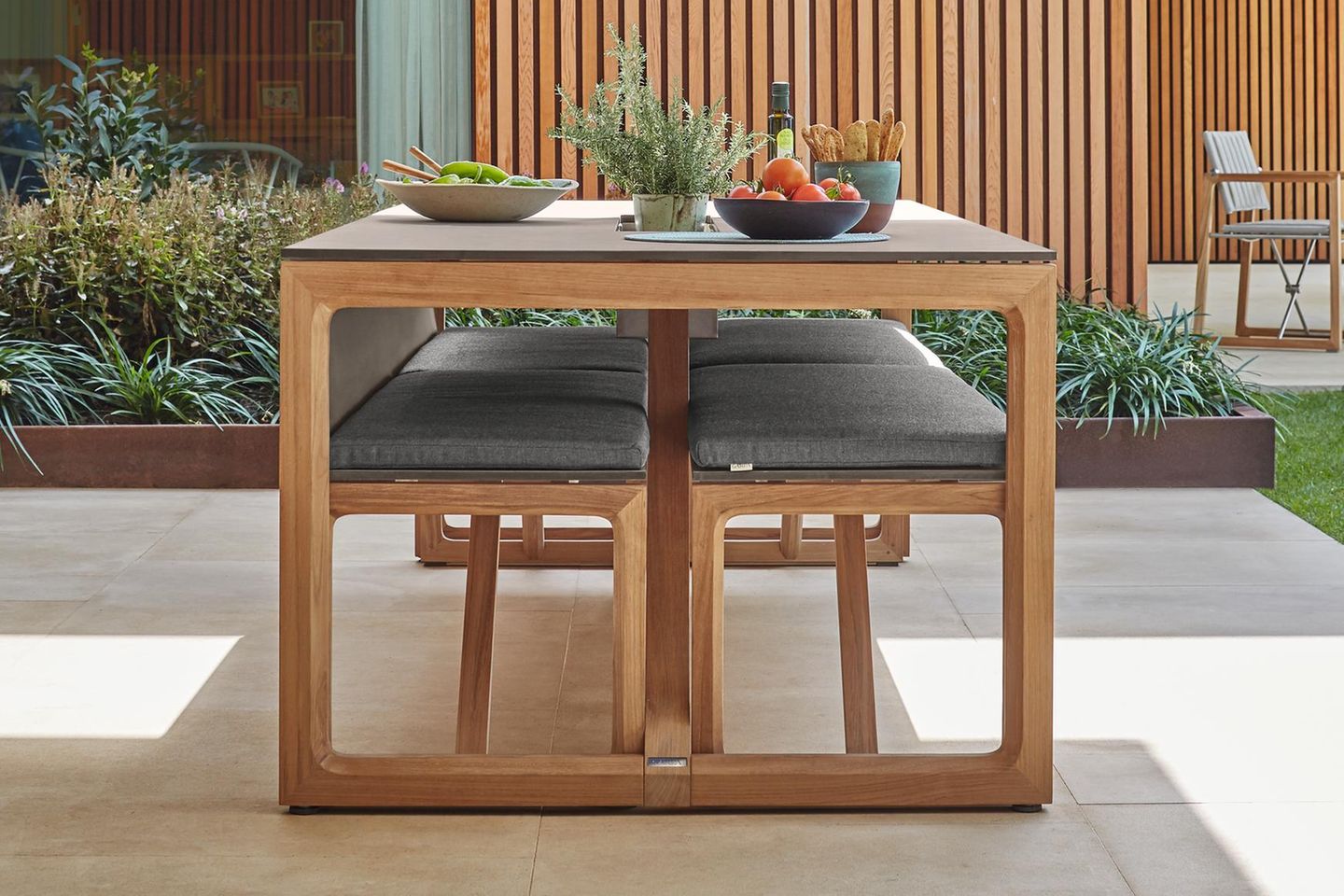 Gartentisch mit passenden Gartenbänken aus Holz mit Polsterung auf einer Terrasse
