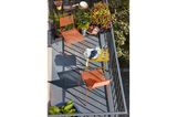Bunte Gartenstühle und ein kleiner Klapptisch auf einem hell beschienenen Balkon