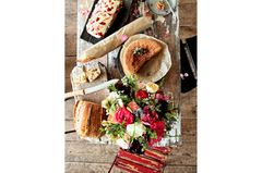 Einfacher Holztisch mit Brot, Kuchen und einem bunten Blumenstrauß