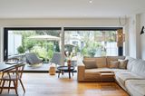 Wohnzimmer mit großer Fensterfront und Ausblick auf die Terrasse