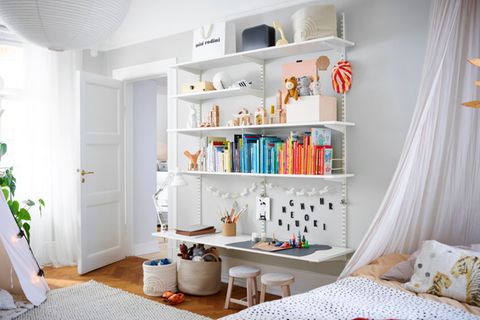Kinderzimmer mit weißer Regalwand und integriertem Schreibtisch