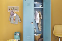 Spindartiger Kleiderschrank aus Metall mit gelber Wand im Kinderzimmer