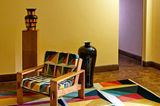 Farbenfroh inszenierter Raum mit Sessel, Teppich und Vasen