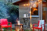 Feuerkorb in einem Schrebergarten mit Gartenmöbeln und Lichterkette