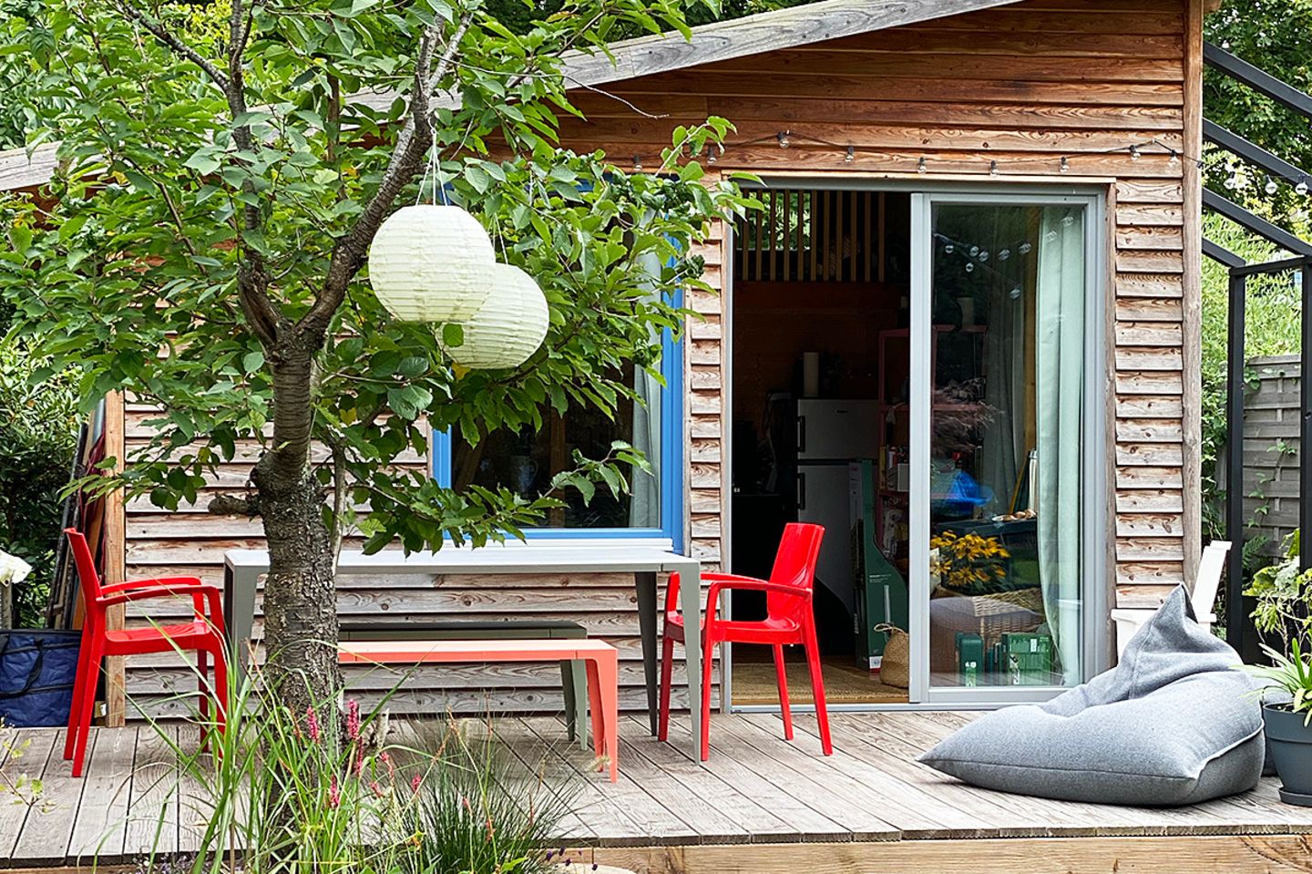Schrebergarten-Laube mit Terrasse, roten Stühlen und grauen Sitzsäcken