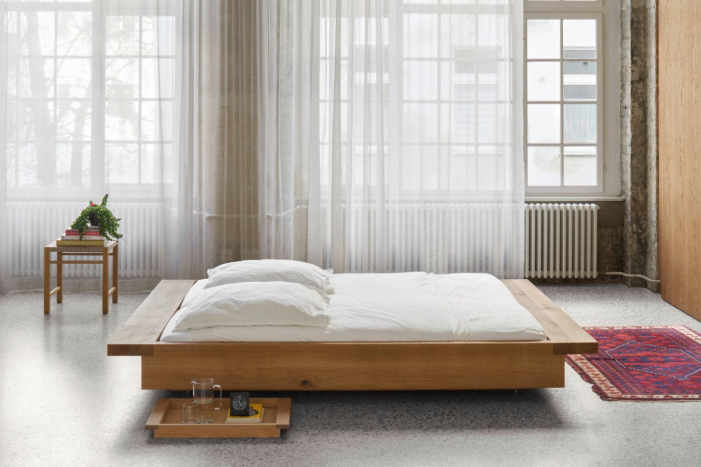 Bodennahes Bett "Noah" aus Holz von e15 in großem Schlafzimmer