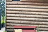 Gartenhaus aus Holz mit einer roten Gartenbank