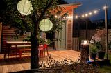 Terrasse einer Gartenlaube mit Lampions während eines Sommerabends