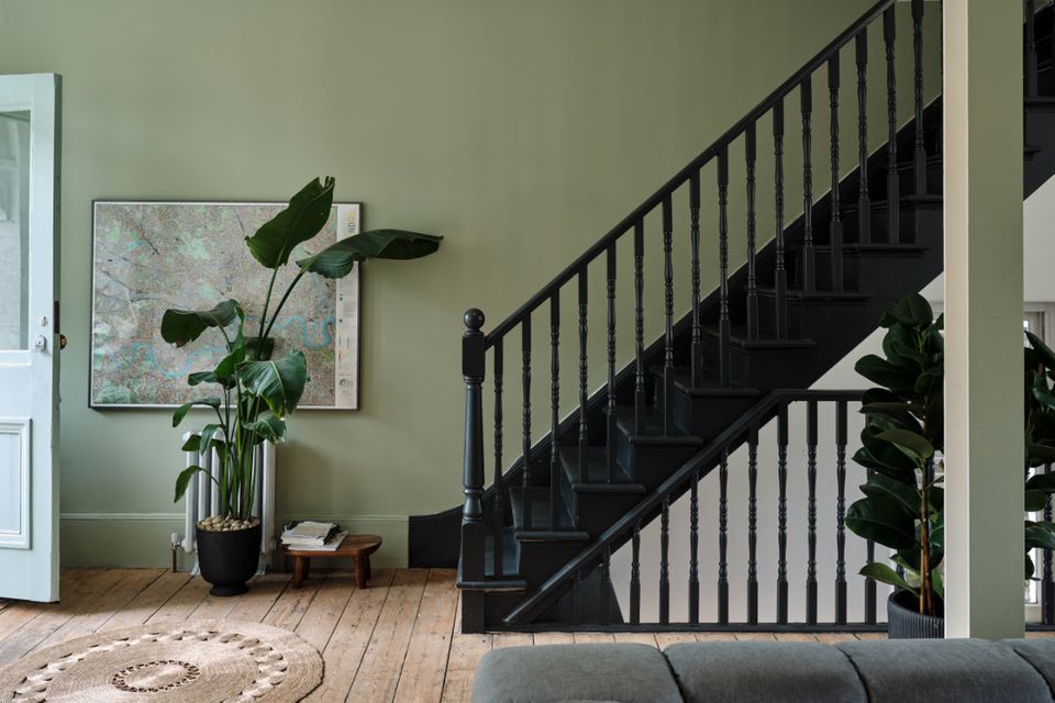 Treppenaufgang mit Wänden in "Grüne Erde" und schwarzem Treppengeländer
