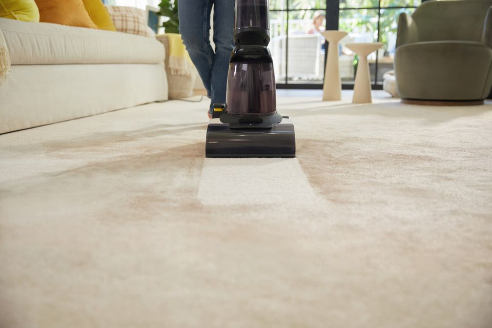 Schmutziger Teppich, der von einer Frau mit dem Teppichreiniger "Carpet One" gesäubert wird