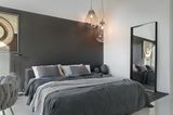 Schlafzimmer mit Doppelbett vor Wand in Anthrazit