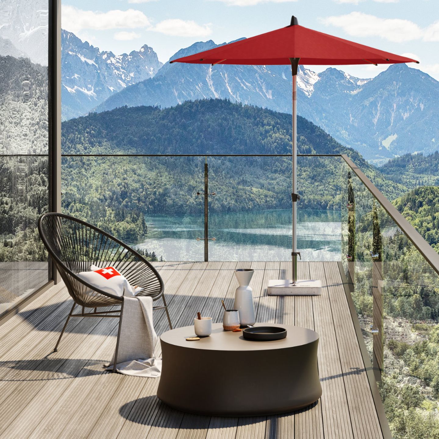 Großzügiger Balkon mit kleiner Sitzecke inklusive rotem Sonnenschirm und beeindruckendem Panoramablick