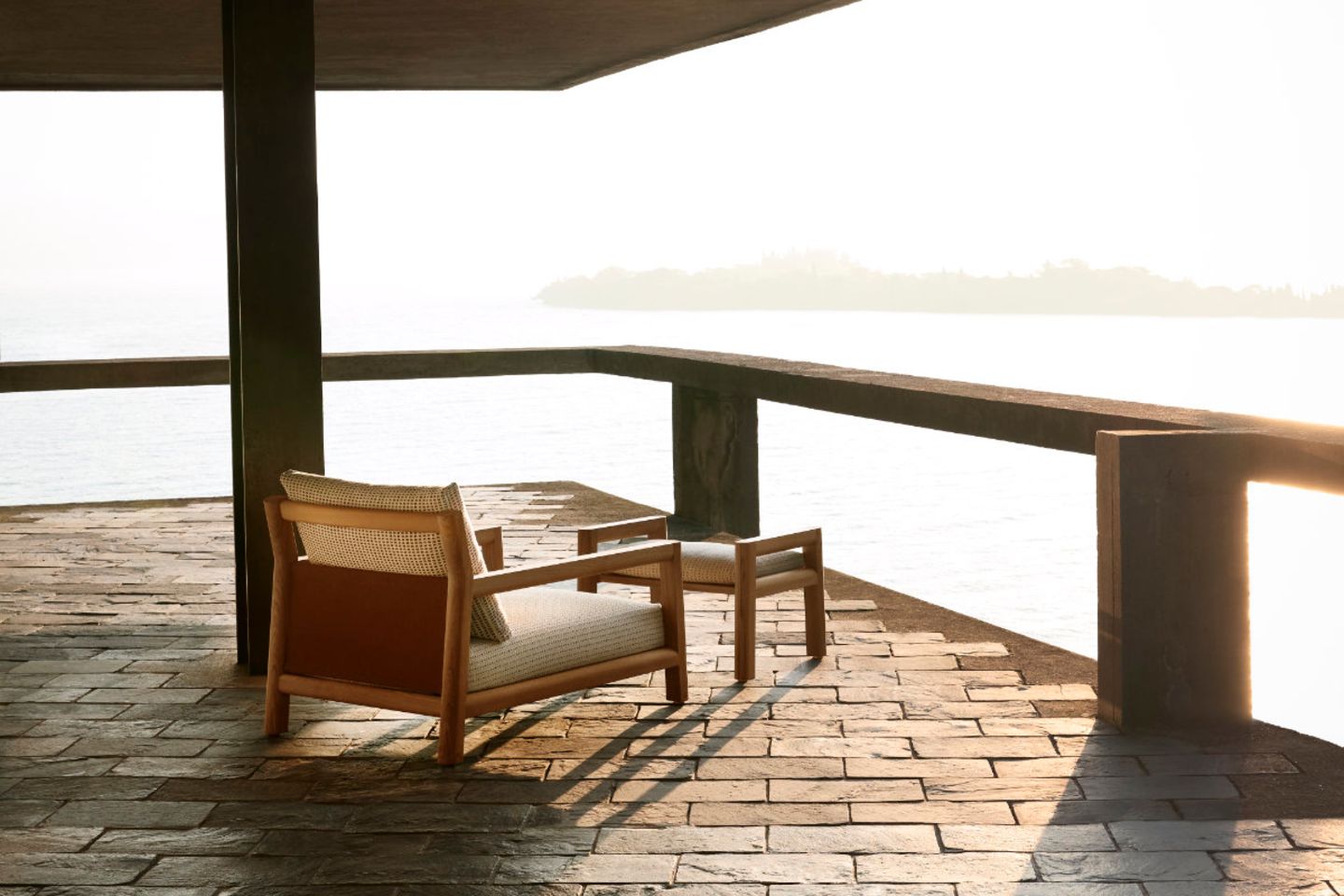 Terrasse mit dick gepolstertem Outdoor-Sessel und Sicht auf den Sonnenuntergang