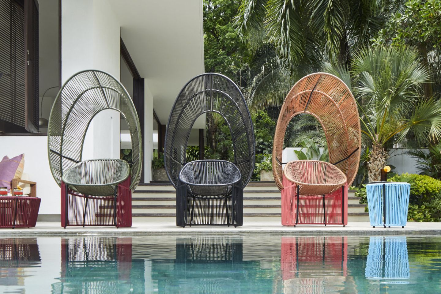 Drei bunt geflochtene Cocoon-Stühle mit Schutzdach am Pool