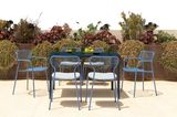 Marineblaue Metallrohr-Stühle um einen Esstisch herum, dahinter Pflanzen als Sichtschutz