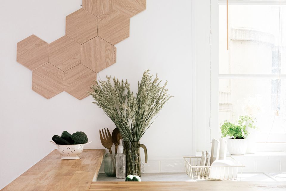 Küchentresen aus Holz im Vordergrund, im Hintergrund hängen Wandpanels in Holzoptik von Nanoleaf