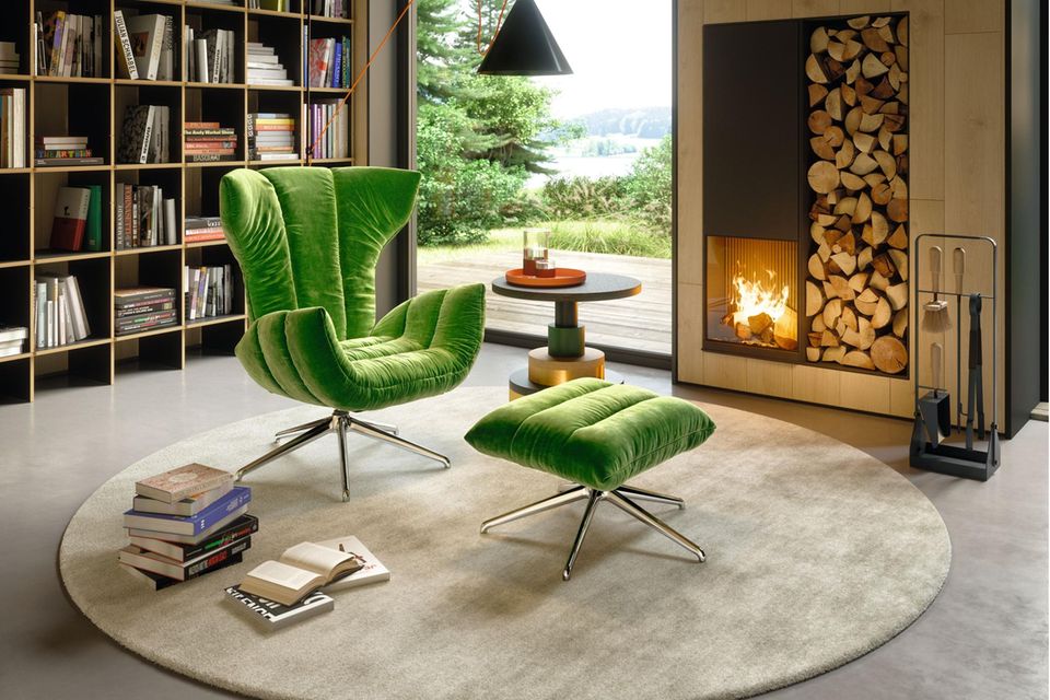 "Cassia"-Lounge Chair von Bretz in Grasgrün vor einem Kamin und einem Bücherregal