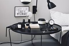 Schlafzimmer mit schwarzem Nachttisch vor weißen Wänden