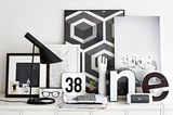 In Schwarz-Weiß dekoriertes Sideboard mit Tischleuchte, Bildern und weiteren Deko-Objekten