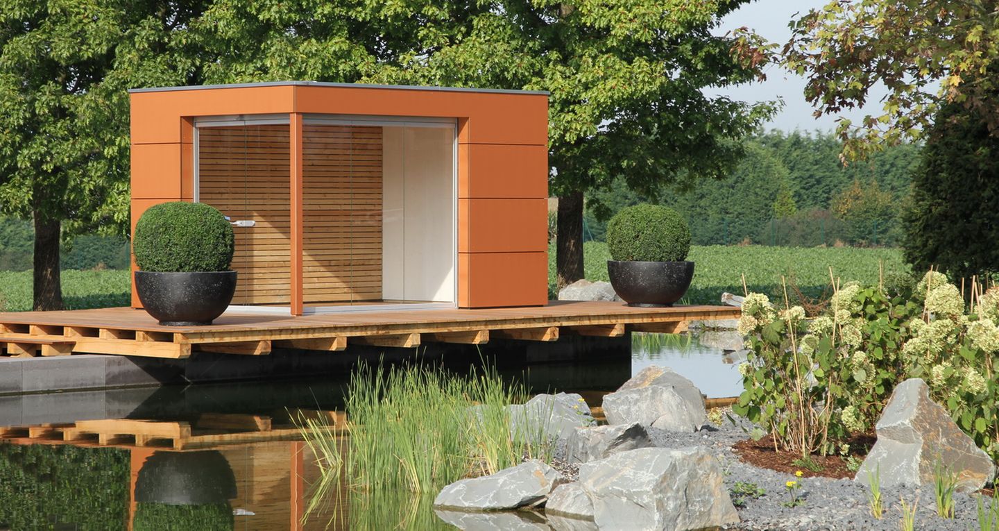 Glas-Pavillon in Orange mit Holzpaneelen auf einem Überbau am Teich