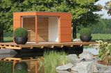 Glas-Pavillon in Orange mit Holzpaneelen auf einem Überbau am Teich