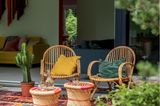 Korbstühle auf einer Terrasse mit farbigem Outdoorteppich