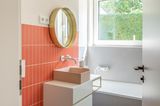 Badezimmer in Orange, Nude und Grau mit einem messingfarbenen Spiegel
