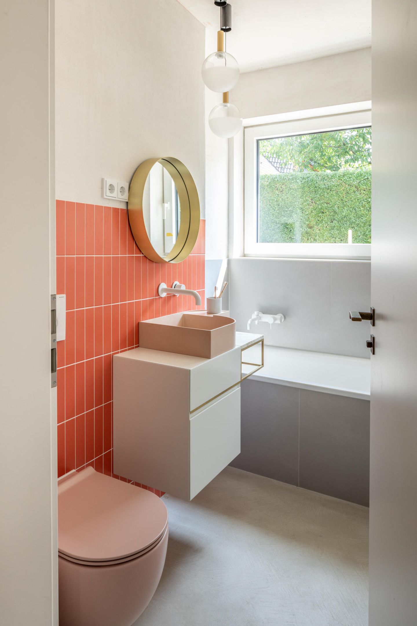 Badezimmer in Orange, Nude und Grau mit einem messingfarbenen Spiegel