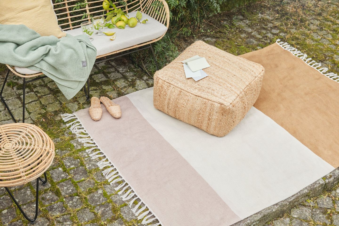 Outdoor-Teppich mit Fransen und Blockstreifen in Rosa, Weiß und Ocker auf Kopfsteinpflaster