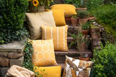 Gelbe Kissen und Decken auf einer Steintreppe in einem grünen Garten