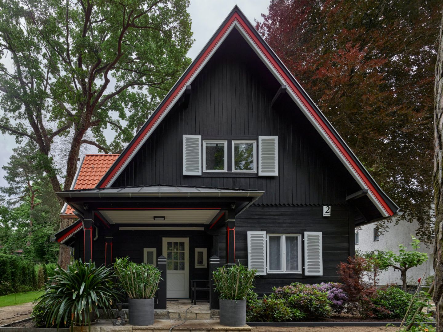 Historisches Holzhaus mit rotem Dach und Vorgarten