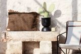 Helle Terrassenwand mit erdfarbenem Kissen und minimalistischem Stuhl im Boho-Stil