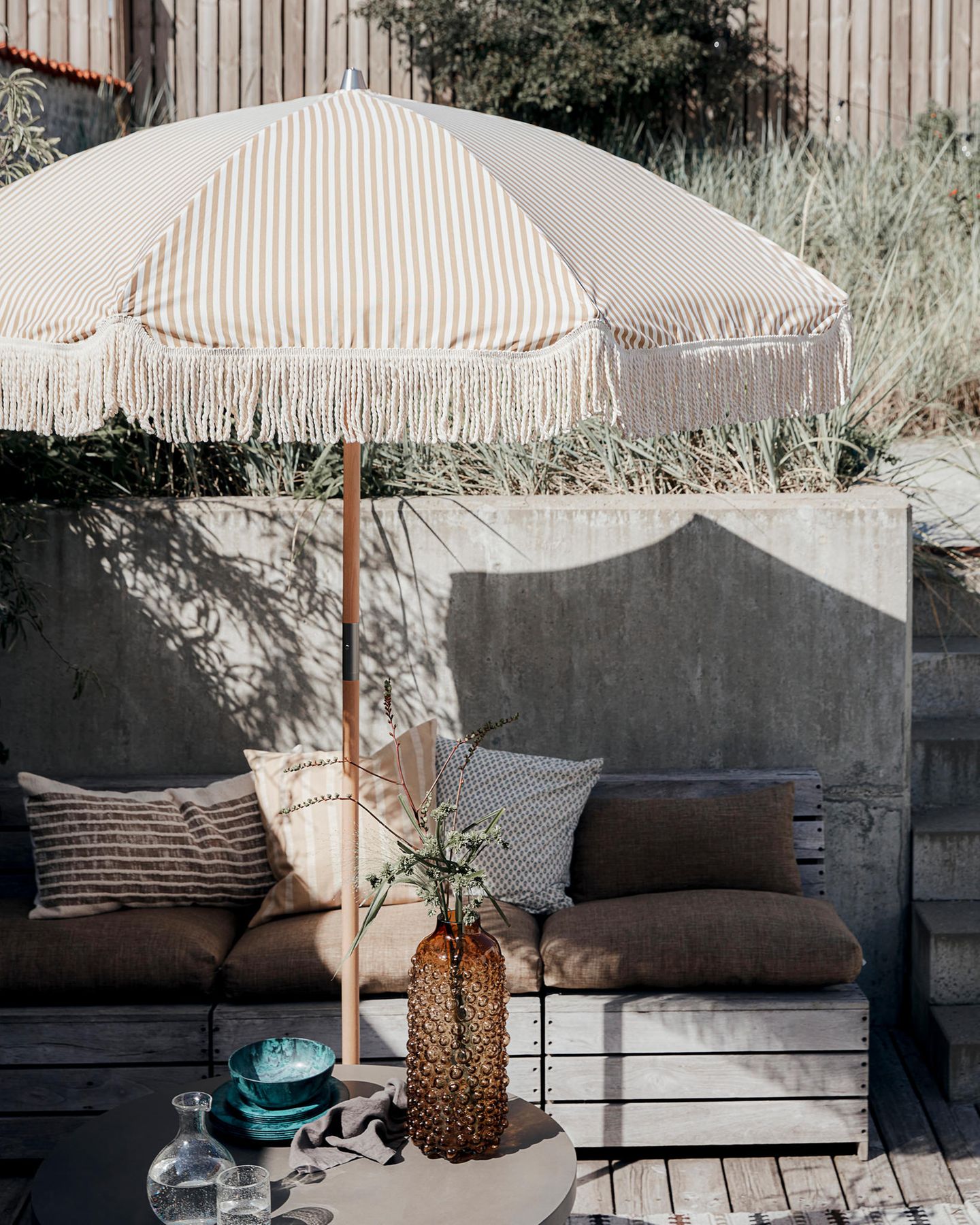 Boho-Terrasse mit Sonnenschirm und Sitzecke in Erdtönen