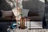 Boho-Terrasse mit Sonnenschirm und Sitzecke in Erdtönen