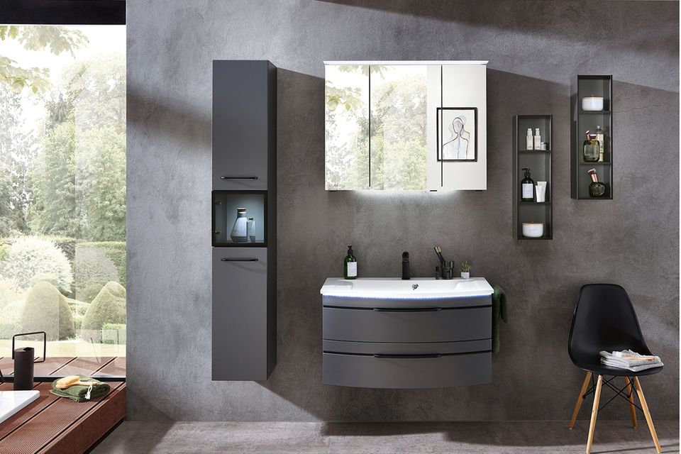 Waschtisch und Badezimmerregal in Schwarz vor einer Betonwand mit Spiegelschrank