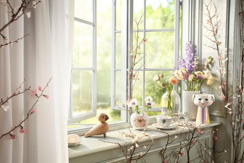 Mit Holzvogel, Vasen und Blumen frühlingshaft dekorierte Fensterbank