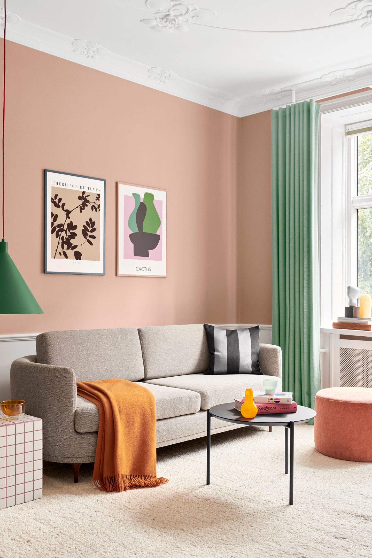 Wohnzimmer mit pfirsichfarbener Wand, weißem Stuck und grauem Sofa