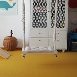 Kinderzimmer mit gelbem Teppich, weißem Schrank und Schaukel im Raum