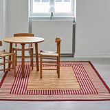 Raum mit großem Streifen-Teppich in Rot und Gelb mi rundem Esstisch und Stühlen