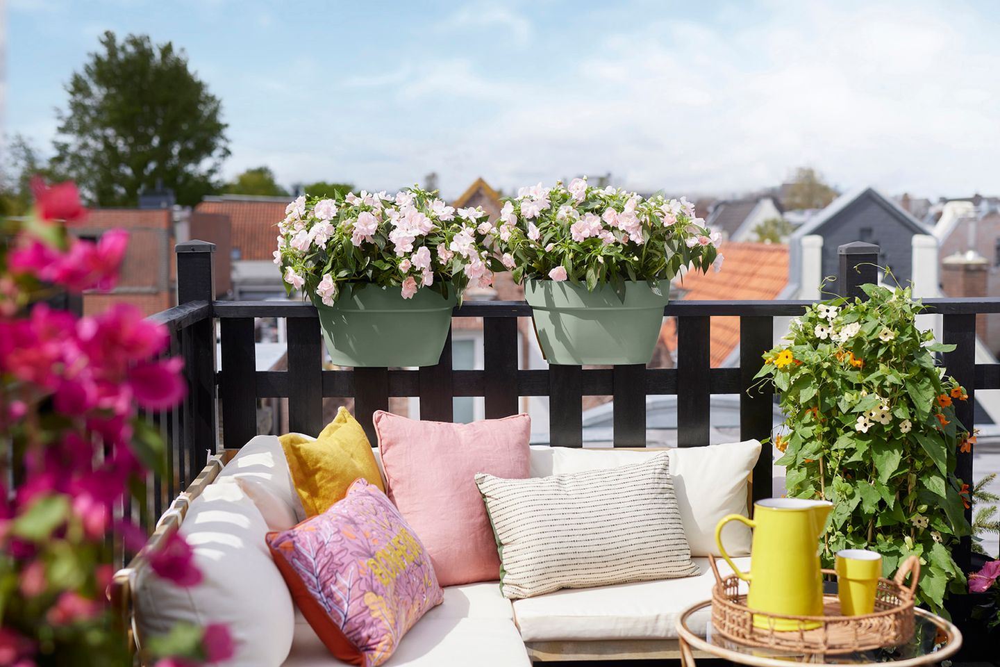 Balkonbepflanzung in hellgrünen Pflanzkästen hinter einem Loungesofa