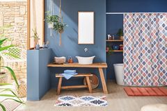 Geräumiges Badezimmer mit Badaccessoires in bunten Farben, Pflanzen und einer blauen Wand