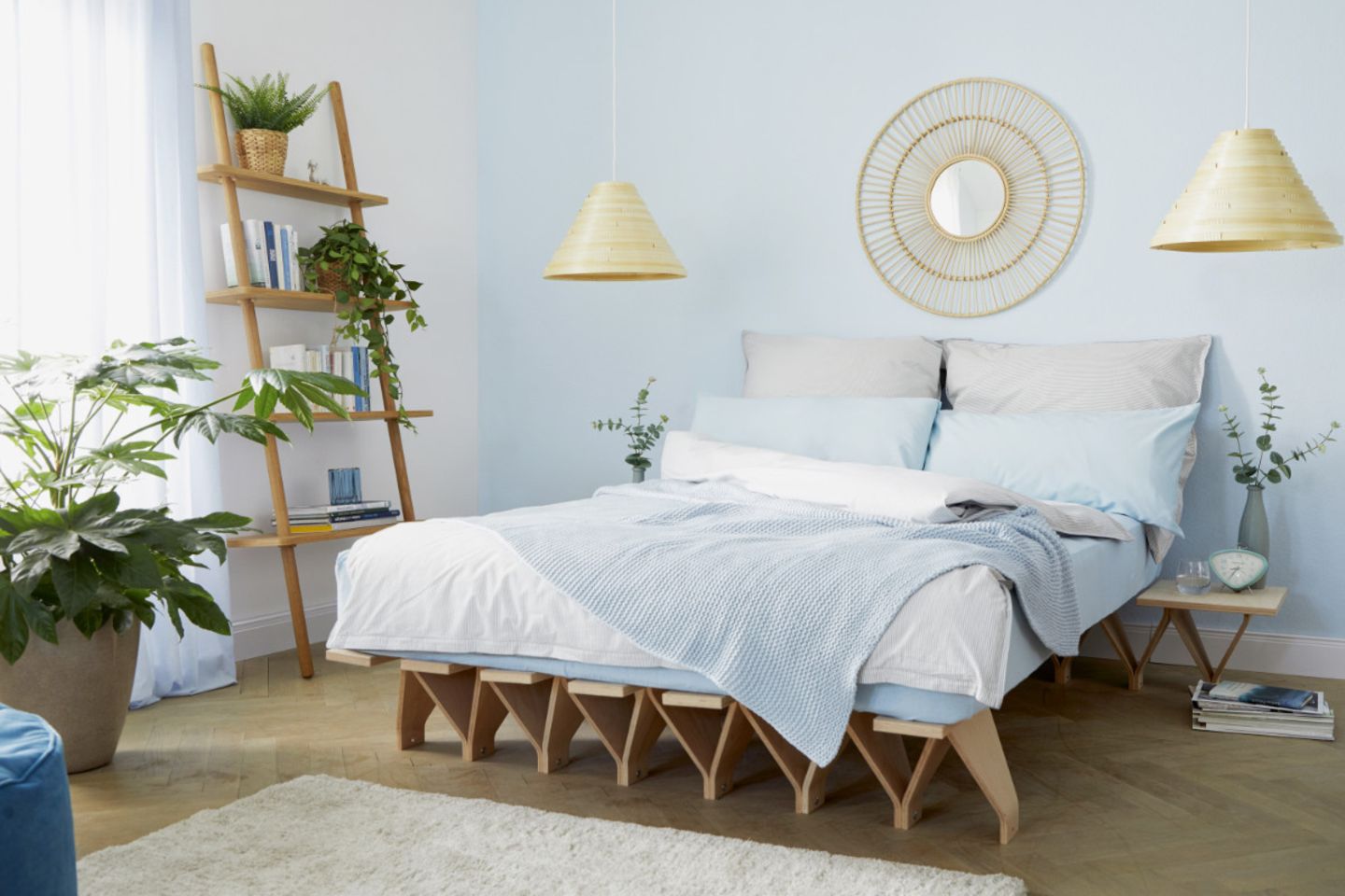 Unter anderem mit Regalleiter, Pflanzen, Wanddeko und Furnierleuchten dekoriertes Schlafzimmer in Weiß und Hellblau