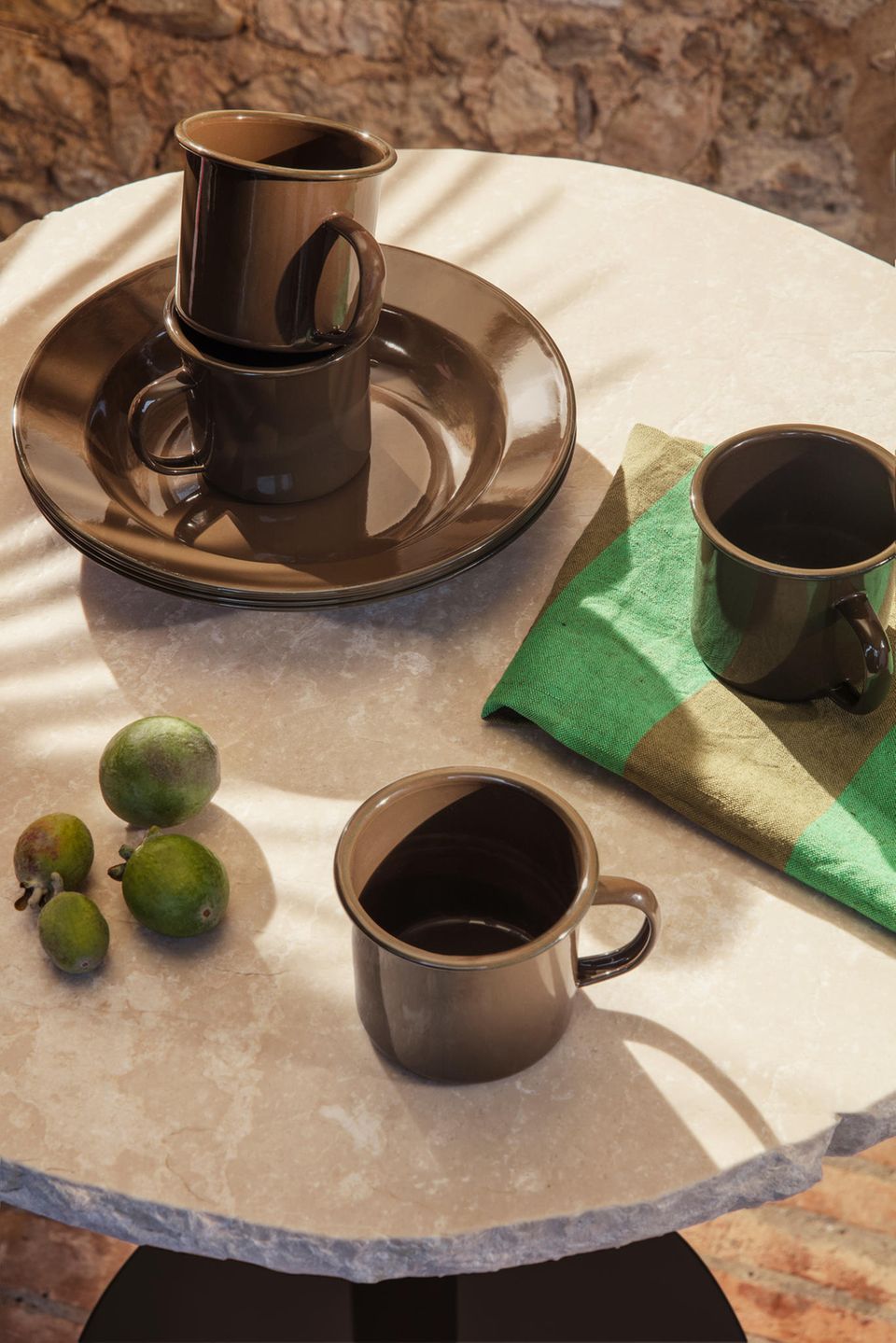 Braunes Geschirr von Ferm Living kombiniert mit einem grün-braunen Geschirrtuch auf einem Marmortisch