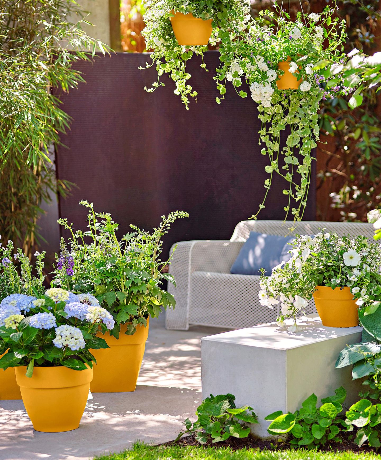 Pflanzkübel in Orange auf einer Terrasse mit Outdoor-Sofa